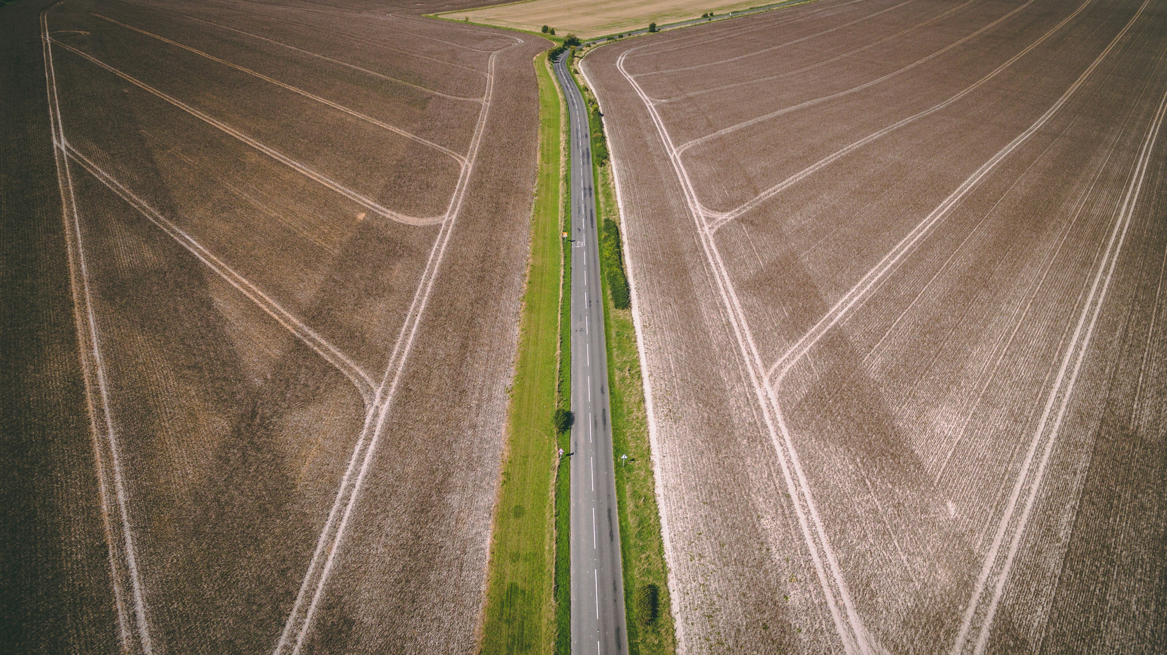 aerial photography of gray concrete road top between brown field during daytime